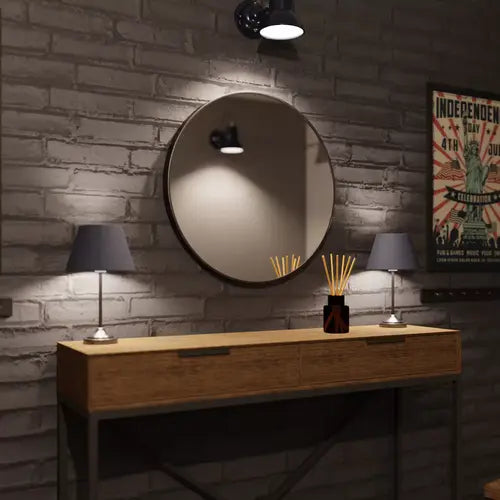 Miroir rond noir de 60 cm placé au-dessus d&#39;une console en bois, entouré de lampes et de décoration murale