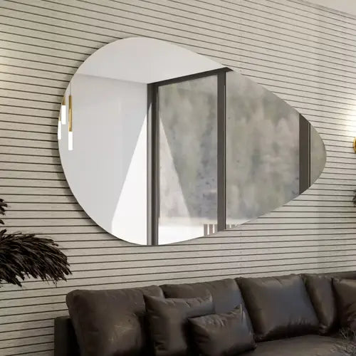 Grand miroir mural en forme de goutte dans un salon lumineux, ajoutant style et profondeur à l’espace avec une vue sur la nature