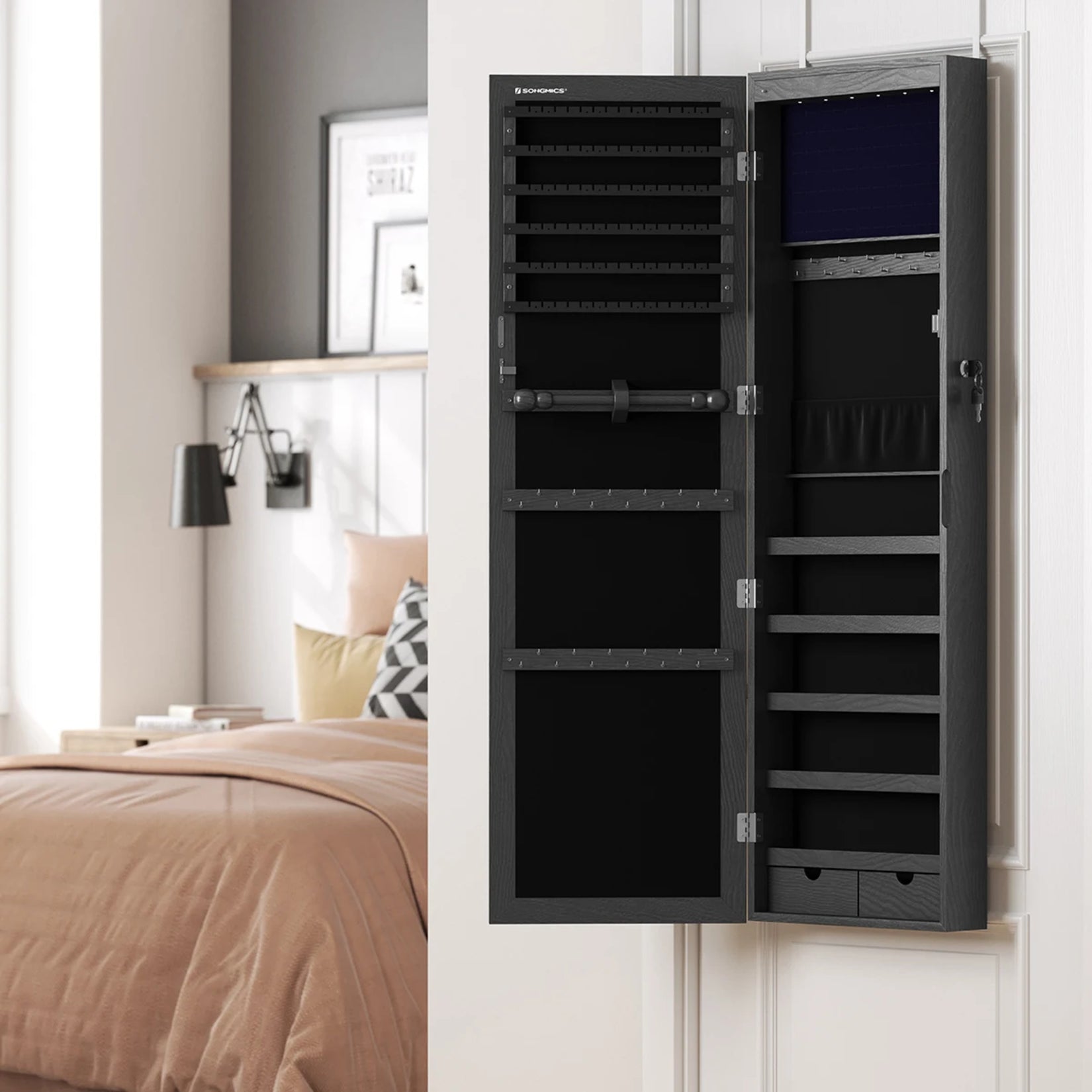 Armoire à bijoux avec miroir noire accrochée à une porte blanche.