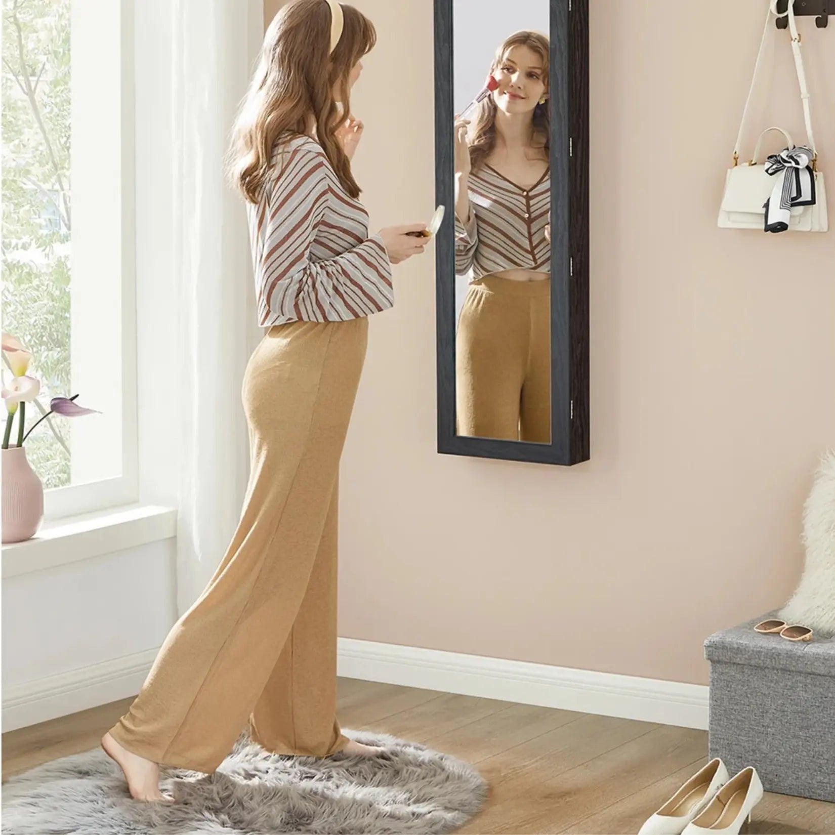 Armoire à bijoux avec miroir noire fixée au mur dans une chambre moderne.