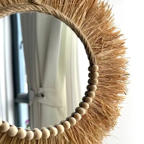 Miroir rond en raphia avec perles en bois, un artisanat fait main.