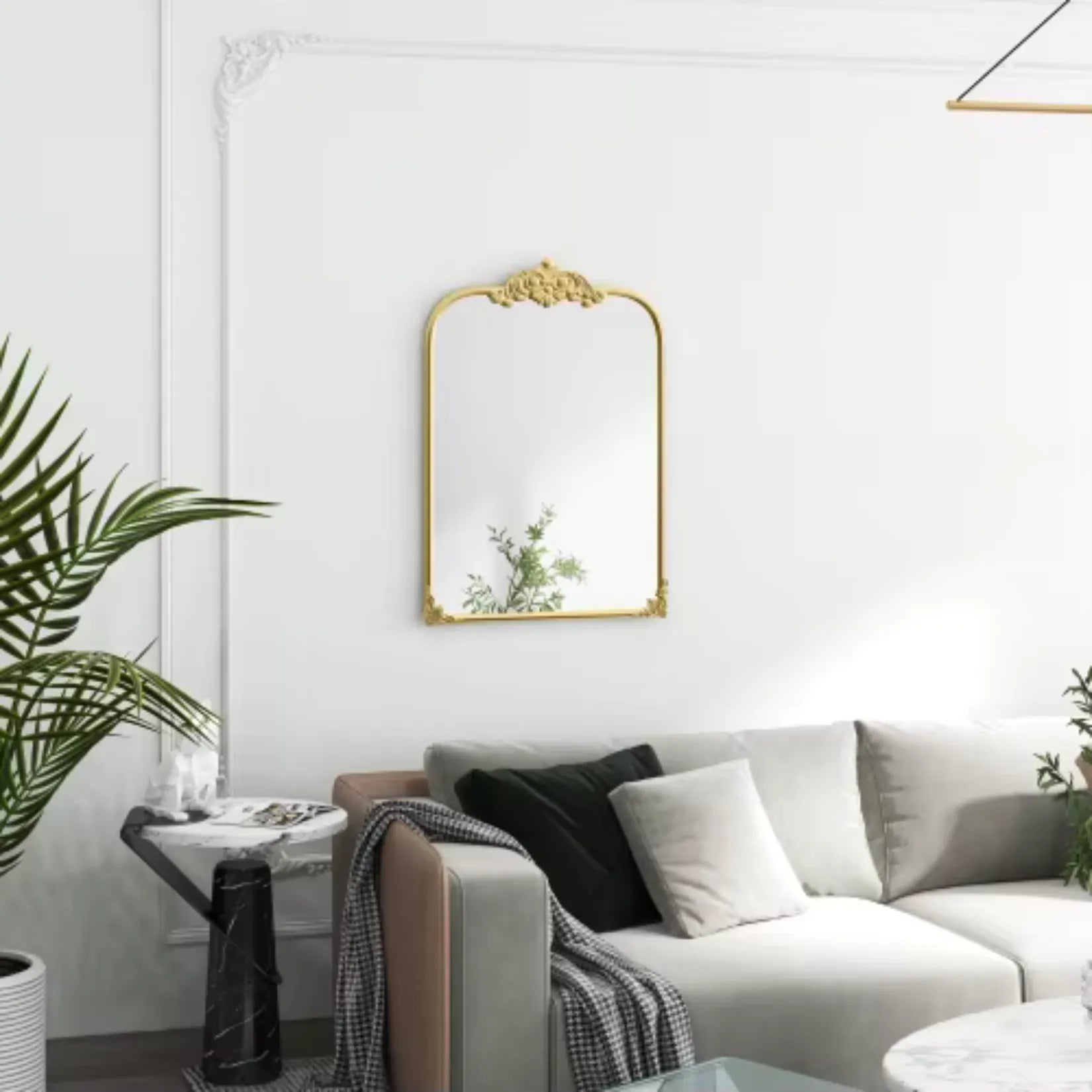 Miroir moulure doré au-dessus d’un fauteuil rose dans une pièce aux tons doux.