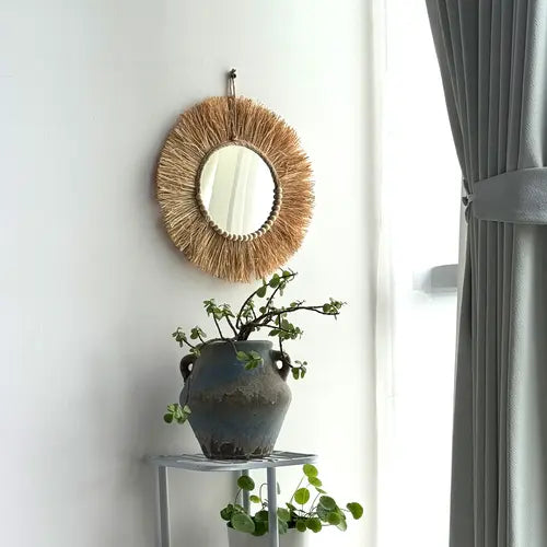 Miroir en raphia suspendu avec un style bohème pour une déco naturelle.