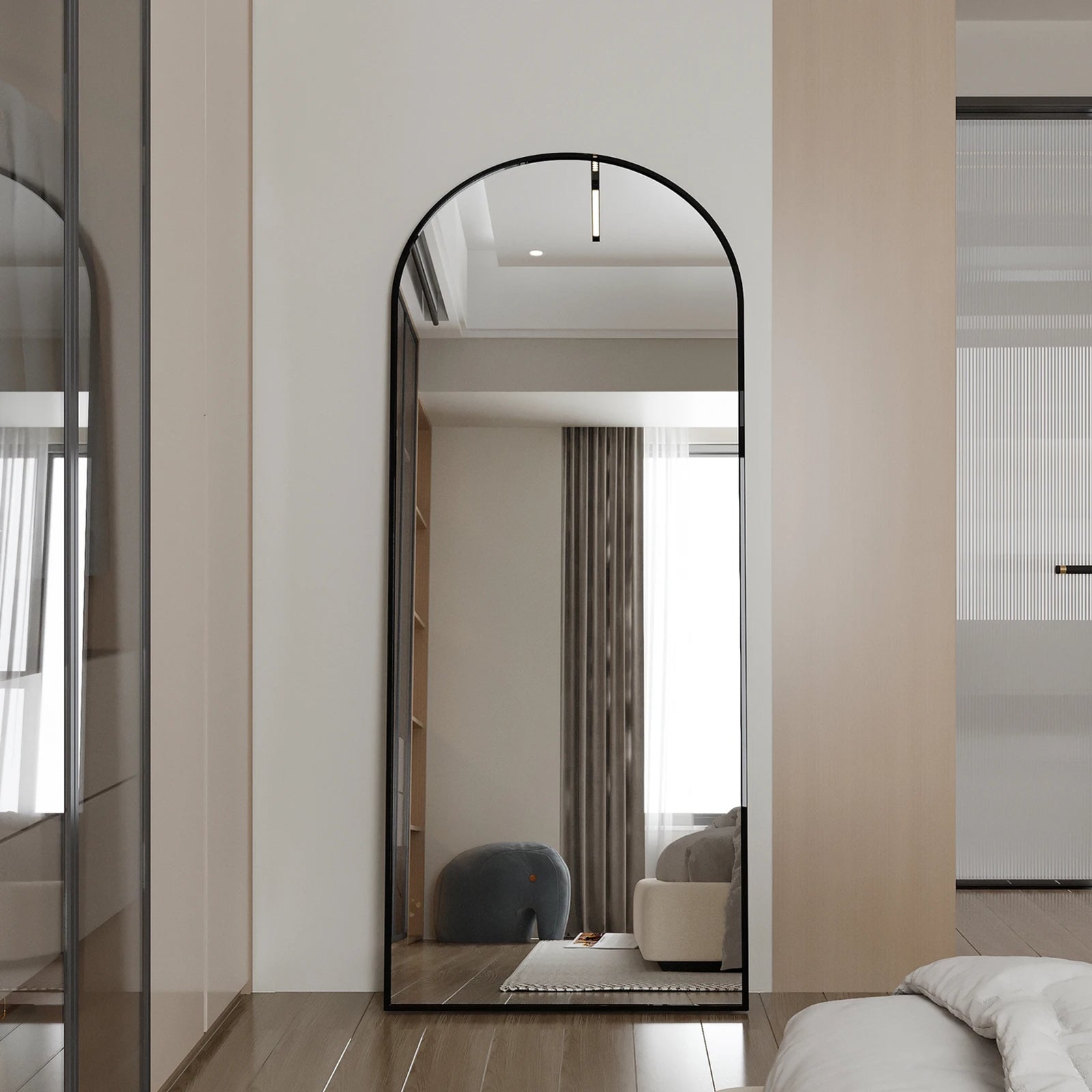 Miroir sur pied noir XXL avec arc arrondi dans un intérieur épuré et lumineux.